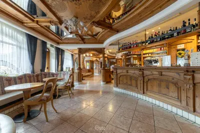 a restaurant with a bar with tables and chairs at Family Hotel La Perla in Fiera di Primiero
