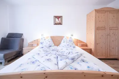 a bedroom with a bed with blue and white sheets at Rasöller Hof in Villandro