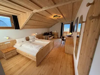 a bedroom with a large bed in a room with wooden floors at Falkenau in Chienes