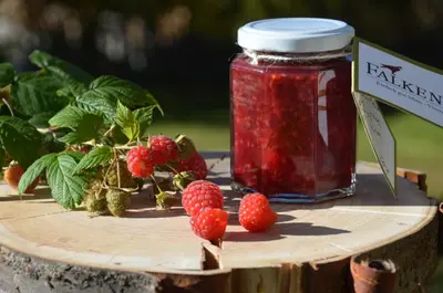 a jar of raspberry jam on a wooden table with berries at Falkenau in Chienes