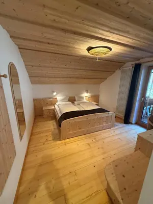 a bedroom with a bed in a room with wooden floors at Falkenau in Chienes