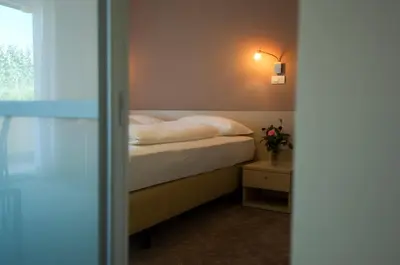 a bedroom with a bed with white sheets and a table at Hotel Weingarten in Caldaro