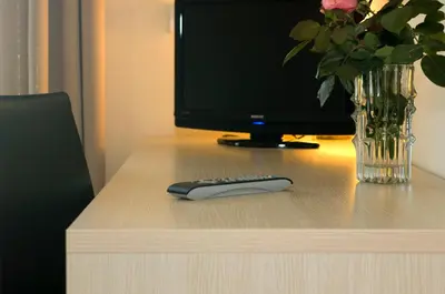 a remote control sitting on a desk with a computer monitor at Hotel Weingarten in Caldaro