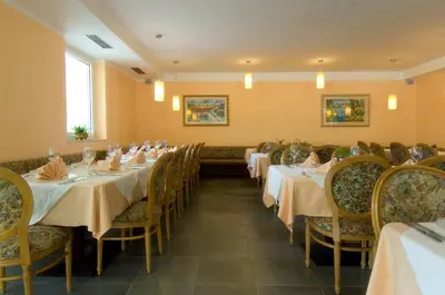 a dining room with tables and chairs with white tablecloths at Hotel Weingarten in Caldaro