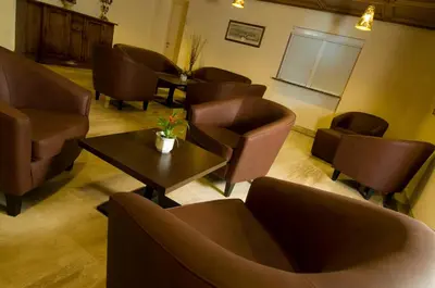 a waiting room with brown chairs and a table at Hotel Weingarten in Caldaro