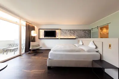 a hotel room with a bed and a balcony at Parc Hotel Am See in Caldaro