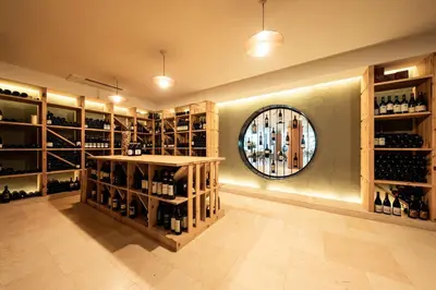 a wine tasting room with a round mirror and wine bottles at Parc Hotel Am See in Caldaro