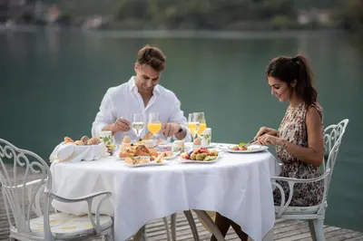 a man and woman sitting at a table eating food at Parc Hotel Am See in Caldaro