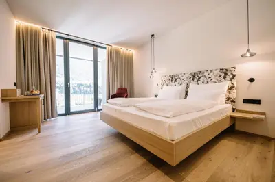 a bedroom with a large bed and a large window at Garni-Hotel Der Forsterhof in Lagundo