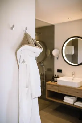 a bathroom with a white robe hanging on a wall at Garni-Hotel Der Forsterhof in Lagundo