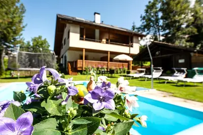a house with purple flowers next to a swimming pool at Haus Bergfrieden Seiser Alm Bahn in Siusi