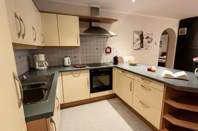 a kitchen with white cabinets and black counter tops at Haus Bergfrieden Seiser Alm Bahn in Siusi