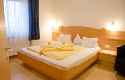 a bed with yellow blankets and pillows on it at Garni Nunnemairhof in Schenna