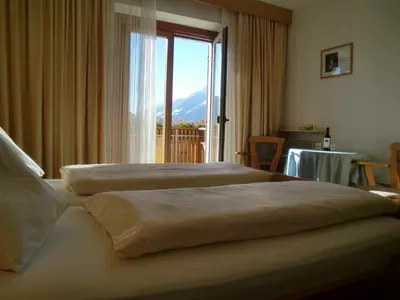 two beds in a hotel room with a large window at Garni Nunnemairhof in Schenna