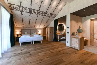 a bedroom with a bed and a coffered ceiling at Dolomites Living Hotel Tirler in Alpe di Siusi