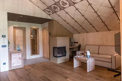a living room with a couch and a fireplace at Dolomites Living Hotel Tirler in Alpe di Siusi