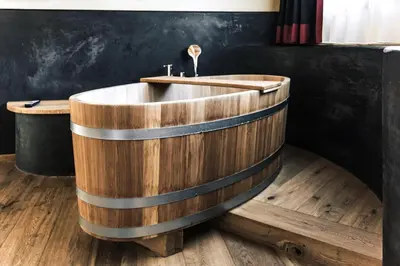 a wooden bath tub with a sink in a room at Dolomites Living Hotel Tirler in Alpe di Siusi