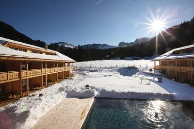 a snow covered building with a pool in the snow at Dolomites Living Hotel Tirler in Alpe di Siusi