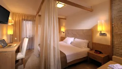 a hotel room with a bed and a desk at Hotel La Perla Wellness & Beauty in Canazei