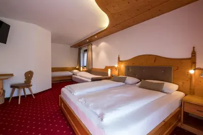 a bedroom with a large white bed and a desk at Garni Alba Bed & Breakfast in Ortisei