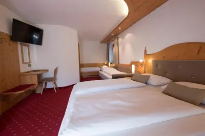 a hotel room with two beds and a flat screen tv at Garni Alba Bed & Breakfast in Ortisei