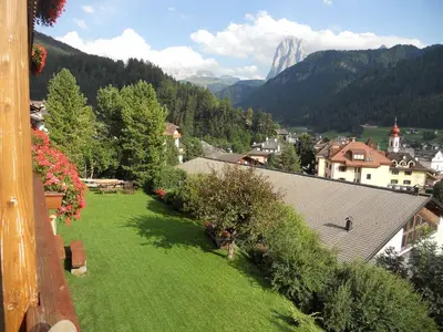 a green yard with a view of a town and mountains at Garni Alba Bed & Breakfast in Ortisei