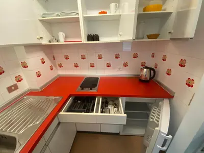 a kitchen with white cabinets and a red counter top at Cësa Panaval Apartments in Santa Cristina in Val Gardena