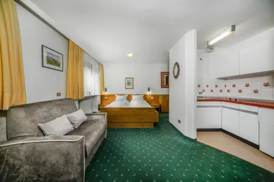 a living room with a couch and a kitchen at Cësa Panaval Apartments in Santa Cristina in Val Gardena