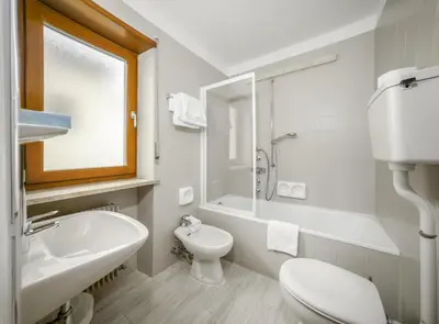 a white bathroom with a sink and a toilet at Cësa Panaval Apartments in Santa Cristina in Val Gardena