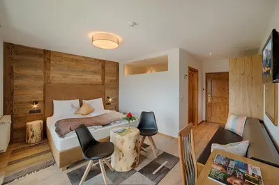 a bedroom with a bed and a table and chairs at Hotel Kristall in Falzes