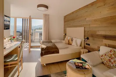 a living room with a bed and a desk and a table at Hotel Kristall in Falzes