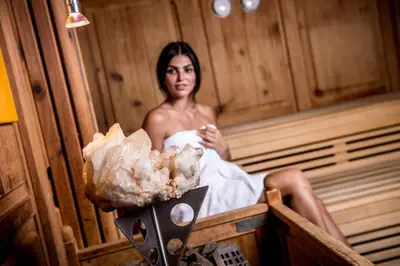 a woman is sitting in a sauna at Hotel Kristall in Falzes