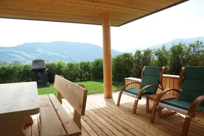 a deck with chairs and a table and a grill at Chalet Frieda in Mühlbach