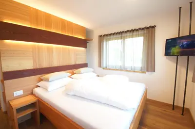 a bedroom with a bed with white sheets and pillows at Chalet Frieda in Mühlbach