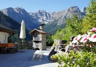 a patio with a stone fireplace and mountains in the background at Agriturismo Grones in San Martino in Badia