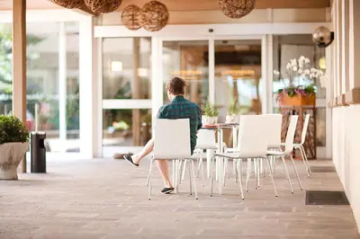 a man sitting on a chair in front of a table at Pension Lichtenburg in Nalles