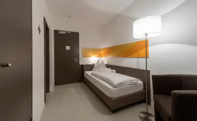 a bedroom with a bed and a lamp and a chair at Pension Lichtenburg in Nalles