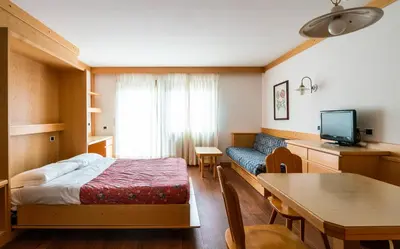 a small room with a bed and a dining table at Apartments Boè in Santa Cristina in Val Gardena