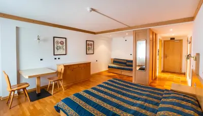 a bedroom with a bed and a desk and a table at Apartments Boè in Santa Cristina in Val Gardena
