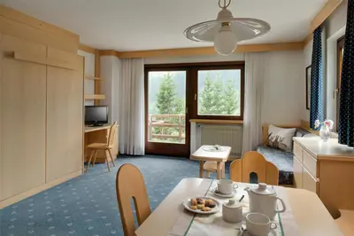 a room with a table and chairs and a kitchen at Apartments Boè in Santa Cristina in Val Gardena