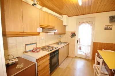 a kitchen with wooden cabinets and a stove top oven at Casa Katia in Canale dʼAgordo