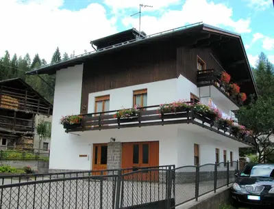 a white house with flower boxes on the balcony at Casa De Biasio PM in Falcade