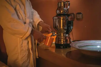 a man is holding a cup next to a blender at Hotel Arnika in Pozza di Fassa