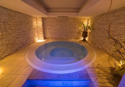 a jacuzzi tub in a room with a brick wall at Hotel Arnika in Pozza di Fassa