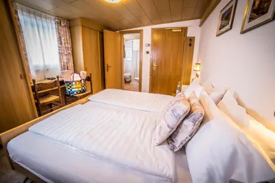 a bedroom with a large white bed with pillows at Hotel Arnika in Pozza di Fassa