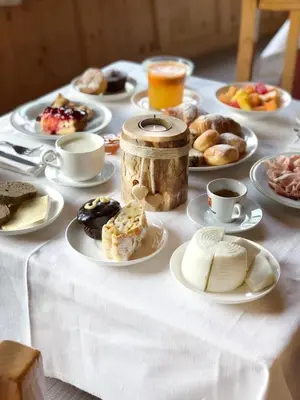 a table topped with plates of pastries and cups of coffee at Park Hotel Bellacosta in Cavalese