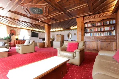 a living room with couches and a book shelf at Park Hotel Bellacosta in Cavalese