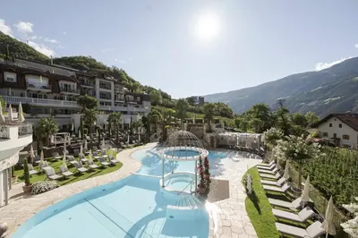 a resort with a swimming pool and mountains in the background at Preidlhof Luxury Dolce Vita Resort in Naturno