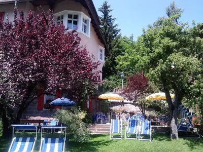 a group of chairs and umbrellas in front of a house at Hotel Villa Emilia in Ortisei