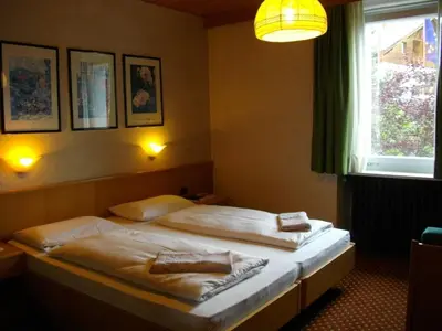 two beds in a hotel room with a window at Hotel Villa Emilia in Ortisei